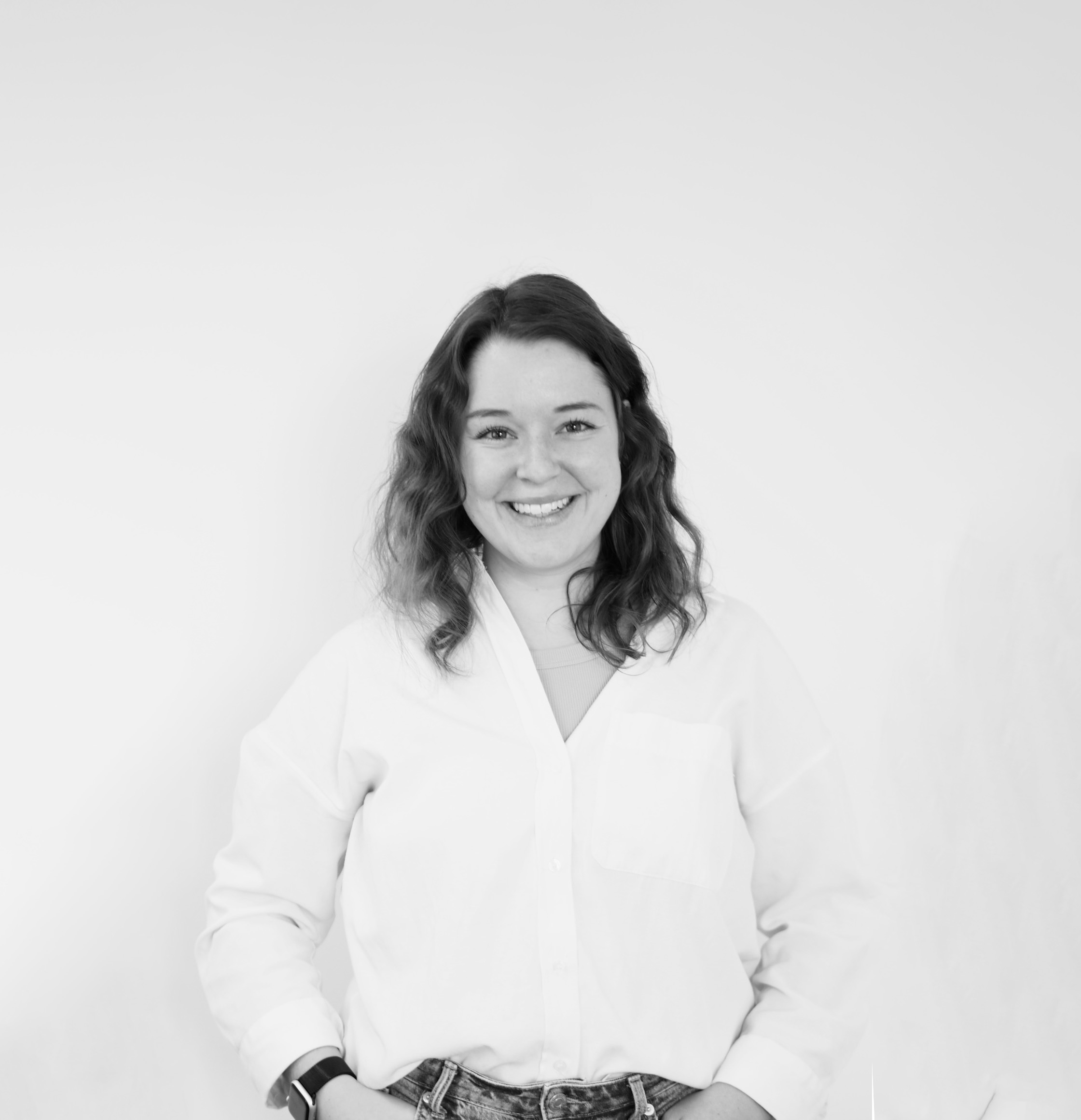 Schwarz-weiß Porträt von Johanna Bonapace, lachend, mit schulterlangen, lockigen Haaren, trägt eine weiße Bluse